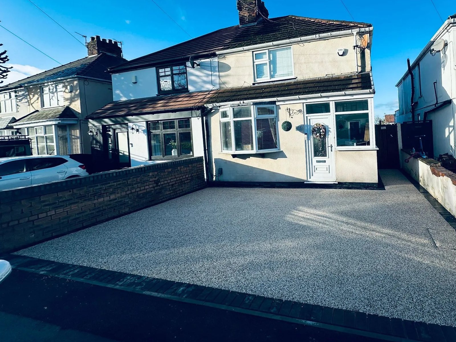 Grey resin-bound driveway with a dark block-paved border in front of a semi-detached house, laid by T&T Driveways
